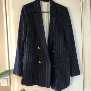 Kritstrecksrandig kavaj  - Kavaj från H&M. Mörkblå med vita kristräck och guldknappar. Knappt använd, inga anmärkningar. 