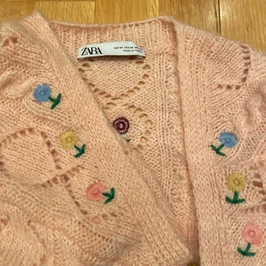 Söt kofta från Zara - Jättegullig stickad kort kofta (mer som ärmar med rygg) från Zara med fina blomdetaljer. Aldrig använd. Storlek M men funkar för S och L också. 