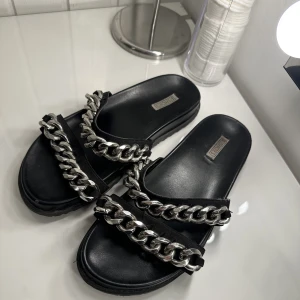 Tofflor från Nelly - Säljer dessa tofflor från Nelly. Tofflorna är använda ett fåtal gånger. Kedjan på är inte i plast, den vägen alltså lite. Säljer då jag inte avänder dem. Skriv för bilder💗