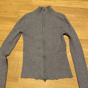 Stickad zip tröja - Grå stickad tröja med dragkedja🌸Sitter tajt och format kroppen, knappt använd🌸Dragkedjan går inte upp hela vägen utan meningen att den ska vara  uppdragen😊