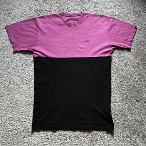 Vans T-Shirt  - Svart/lila Vans colourblock t-shirt. Finns ett litet hål precis under ärmen på den, syns knappt när man bär den men kan ses på andra bilden. Annars mycket bra skick