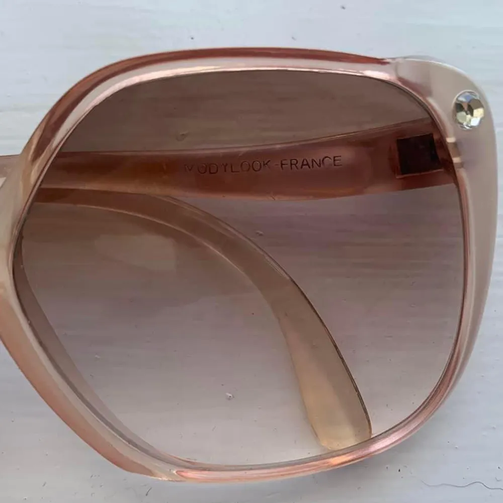 Glammiga 70-tals bågar!  Ljusrosa solglasögon från ”Modylook Gigi Paris”. En liten gnistrande diamant på ena bågen. Skicket är mycket bra, bara någon ytlig repa på glaset.  Skalm-skalm: 14 Bågens storlek ca: 6.5x6  Pris inkl frakt . Accessoarer.