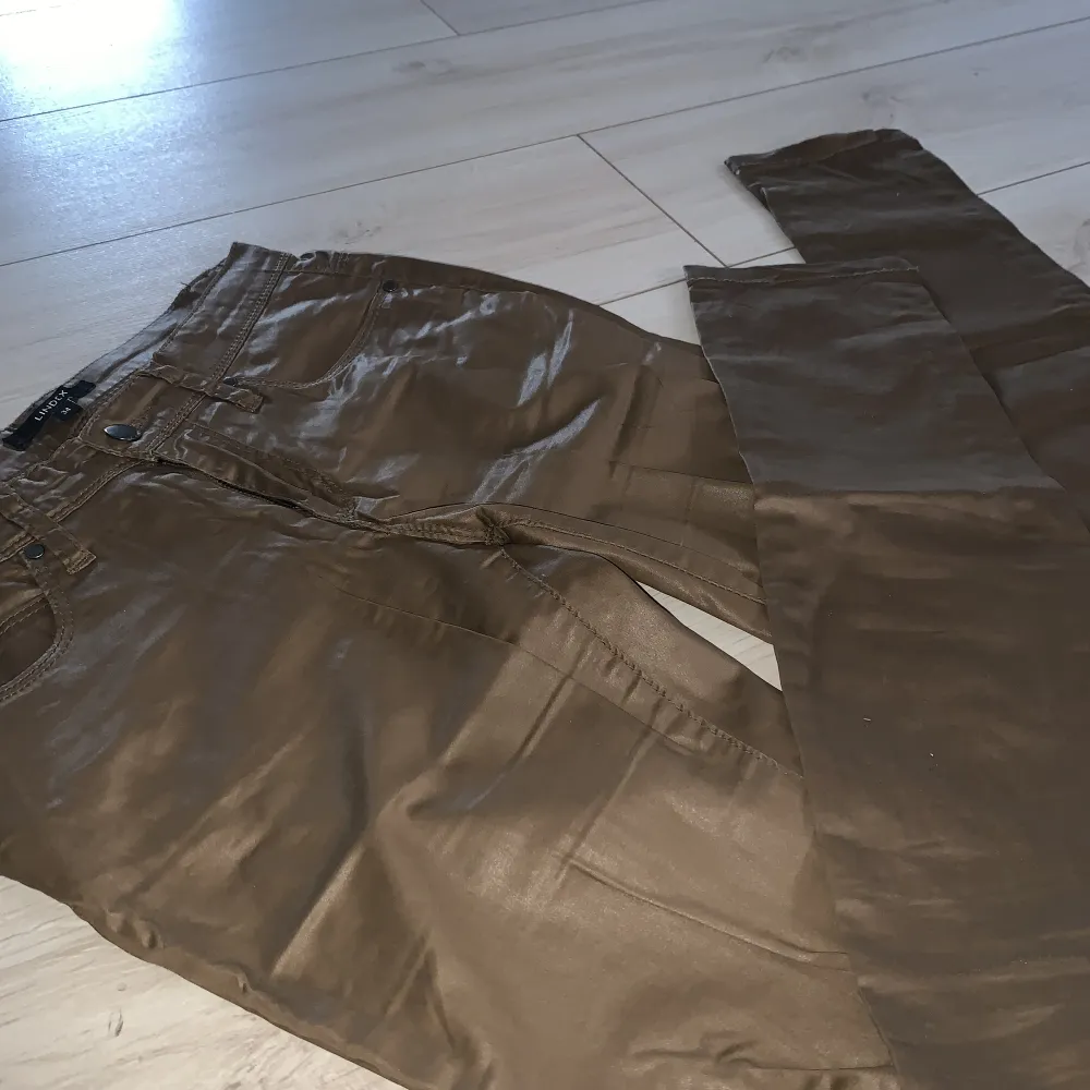 Extremt snygga byxor i läder-aktigt tyg. Brun färg och glansig till yta. . Jeans & Byxor.