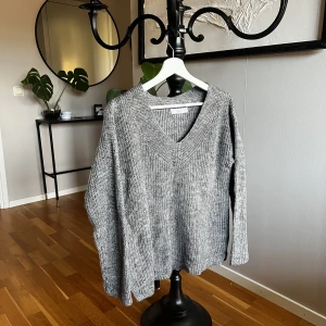 Grå stickad tröja - V-ringad stickad tröja. Mörkgrå