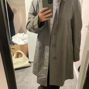 Grå trenchcoat  - Rejäl trenchcoat ingår färg och tjockt material. Köpt secondhand. Endast använd en gång, bra skick. Hör gärna av dig vid frågor eller för fler bilder🤗