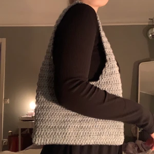 Virkad axelväska - Säljer min virkade axelväska. Den är gjord i ett grå/blått garn i 100% akryl. Axelbandet är ca. 60 cm långt. Priset kan diskuteras. Frakten ingår ej🌻🥰