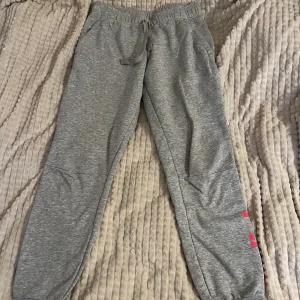 Adidas träningsbyxa - Sköna adidasbyxor som inte kommer till användning längre, dom är lågmidjade med snörning i midjan. Står adidas på ena benet i rosa