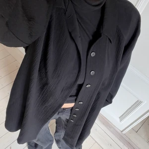 Svart kappa - Tunn svart kappa med cool textur. Perfekt att ha nu på tidig höst eller i vår. En knapp saknas men annars i utmärkt skick. Köppt på loppis.