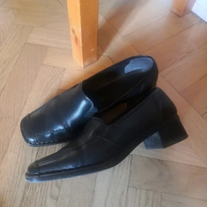 Svarta Loafers strl 39 - Snygga svarta loafers i skinn med fyrkantig tå och lite klack. Normala i storlek. Fint skick.