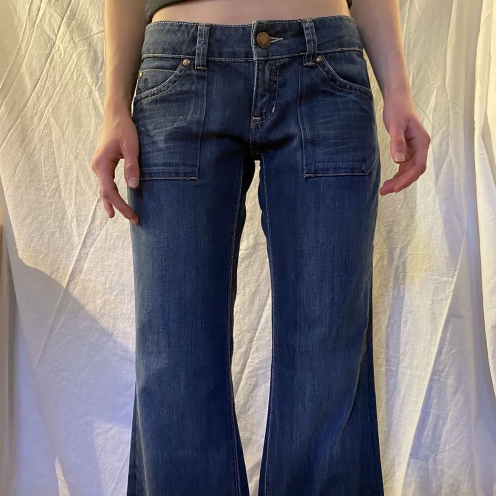 Skitsnygga lågmidjade vida/bootcut jeans. Så fina fickor både fram och bak! Säljer då de är lite för små😭 Modellen på bilden är ca 173cm lång, midjemåttet är 42cm och innerbenslängden är 82cm. Hör av dig vid frågor eller intresse!🥰💕. Jeans & Byxor.