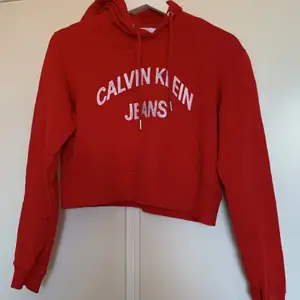 Röd croppad hoodie från calvin klein. Texten på hoodien är sliten från tvätt. nypris låg runt 900 men säljer den för 200 då den är rätt så använd