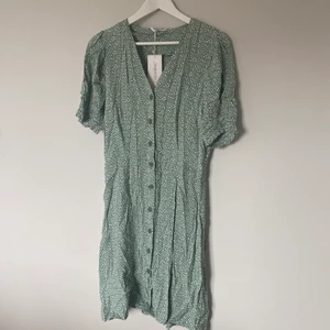 Grön prickig klänning med knappar - Jättefin grön klänning med knappar, helt oanvänd med lappen kvar! Storlek L men något liten i storleken så passar M också. Köparen står för frakt 💚