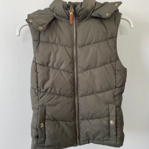 Grön väst  - Väst i fin grön färg med luva och fickor! Sparsamt använd så i väldigt bra skick! 