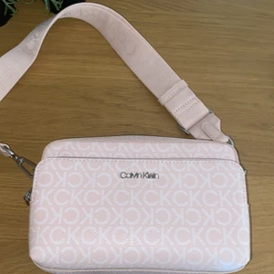 Calvin Klein väska  - En äkta rosa Calvin Klein väska som är helt oanvänd och är i nyskick. Man kan ha mycket grejer i den då fickorna är stora. (Priset kan diskuteras) 