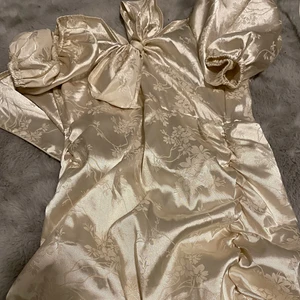 Silvrig klänning - En slät silvrig klänning med en knut uppe,  Dragkedja bak. 