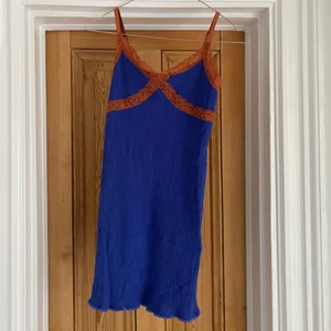 Klänning Urban outfitters - Jättefin klänning från Urban outfitters, mörkblå med spetsdetaljer i orange/brons/brunt, strechig och ganska kort. Inköpt förra året men sparsamt använd. 