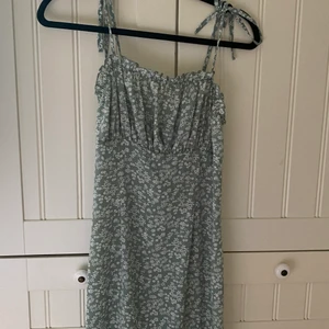 Sommarklänning - Jättefin tight sommarklänning i småblommigt grönt tyg med rysch framtill. Använd endast några få gånger, fint skick. Hör av dig vid intresse/fler bilder.  Köpare står för frakt.