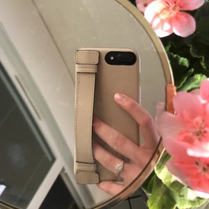 Mobilskal med handrem  - Ett mobilskal från H&M som är använt max 2 gånger vilket var 2 korta stunder den blev använd innan jag tog av den igen, så man kan säga att den är helt ny.  Nypris: 99kr - säljer för 50kr + frakt, om man vill mötas upp så är frakten gratis!