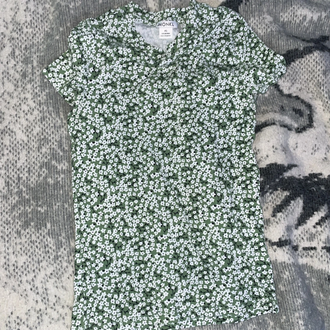 En grön tröja med vita blommor på - 91