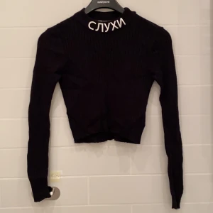 Svart stickad tröja - En långärmad och tunn stickad tröja med motiv, kan användas som crop topp. Är slimmad. 