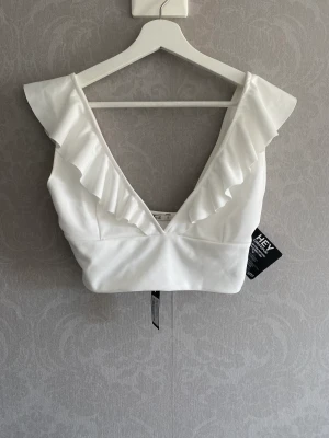 Topp med volanger  - Superfin Vit topp med volanger Perfekt till studentveckan!  Storlek: Small  Aldrig använd, prislappar sitter kvar