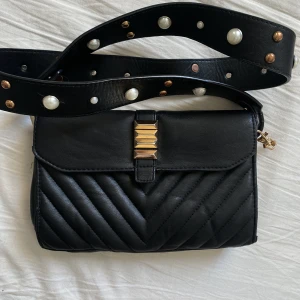 Svart handväska  - Svarthandväska med detaljerat axelband.  Skickar även med två andra axelband Ett svart tunt och ett bredare ormmönsrat band 