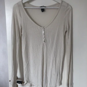 Långärmad tröja - Långärmad tröja med knappar fram, långa armar som går ner äver handleden. Tunnt mjukt tyg