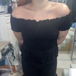 Svart off shoulder - Svart t-shirt med volang från Gina Tricot. Storlek S men passar både större och mindre pga smockningen. Finns i gul också.