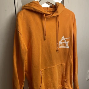 Tommy Jeans Hoodie - Säljer en Tommy Jeans Hoodie i utmärkt skick! Hoodie är stor i storleken och knappt använd. Orange färg med vitt tryck med inga skador, slitningar eller skavanker! Köpt i Nk göteborg 5/5 Skick   Storlek M