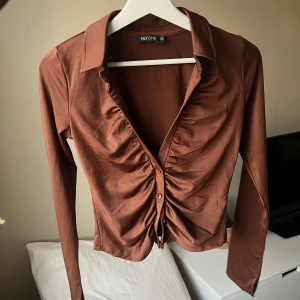 Topp från Nelly, strl xs  - Snygg brun topp med urringning, strl xs. Aldrig använd, 50kr 🤎