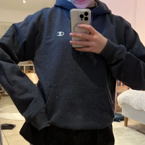 Champion hoodie - Mörkgrå hoodie från Champion. Stl M men skulle säga att den sitter mer som en S. Ljusgrå inuti luvan. Köpt second hand. Lite nopprig men annars bra skick!!!