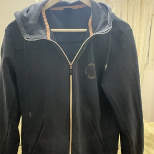 Hugo boss kofta - Väldigt fin kofta med väldigt bra tyg. Värmer en och får en att se stilig ut. Haft koftan i 1 år. Går att matcha med alla sorters byxor. Bra stolek på fickorna och väldigt bekväm luva.