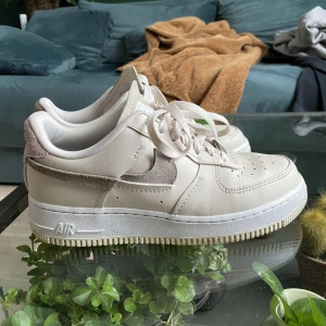 Nike Air Force 1 - Ljusbeiga med bruna och rosa detaljer, i gott skick! Storlek 38,5 Frakt ingår i priset!