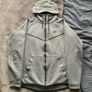 Nike tech fleece  - En grå Nike tech fleece kofta i storlek herr M. Denna modell med snören till luvan är ovanlig. Koftan är i mycket bra skick. Skriv till mig för fitpic, mått på plagget eller annat. Kan fraktas eller mötas upp i Malmö/Lund.