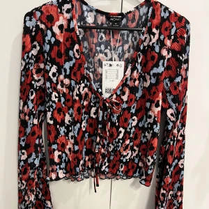 Blus/topp från monki, oanvänd  - Blommig topp från monki i storlek M där lappen finns kvar. Knytning vid brösten/magen