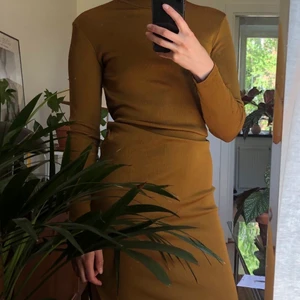 Guldig klänning från h&m storlek 36 - Guldig klänning från h&m storlek 36. Halv polokrage och dragkedja i sidorna längs benen så man kan ha slits på ena eller båda sidorna om man vill.   Väldigt stretchig och lite större i storleken så passar 36-38  Använd ett fåtal gånger