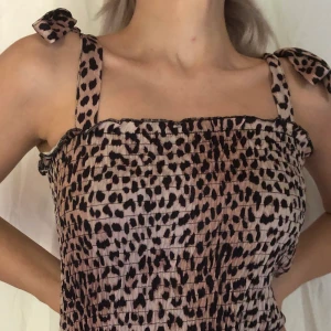 Topp - Topp i leopard-mönster. Söta detaljer på axlarna där man kan knyta rosetter. 