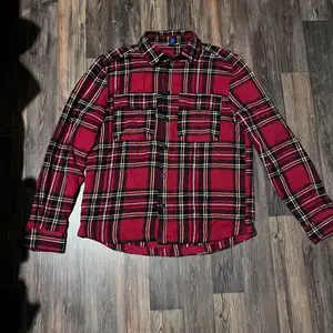 En rödrutig overshirt/skjorta gjord i bomull Köpt på second hand men skulle säga den är i jättebra skick.