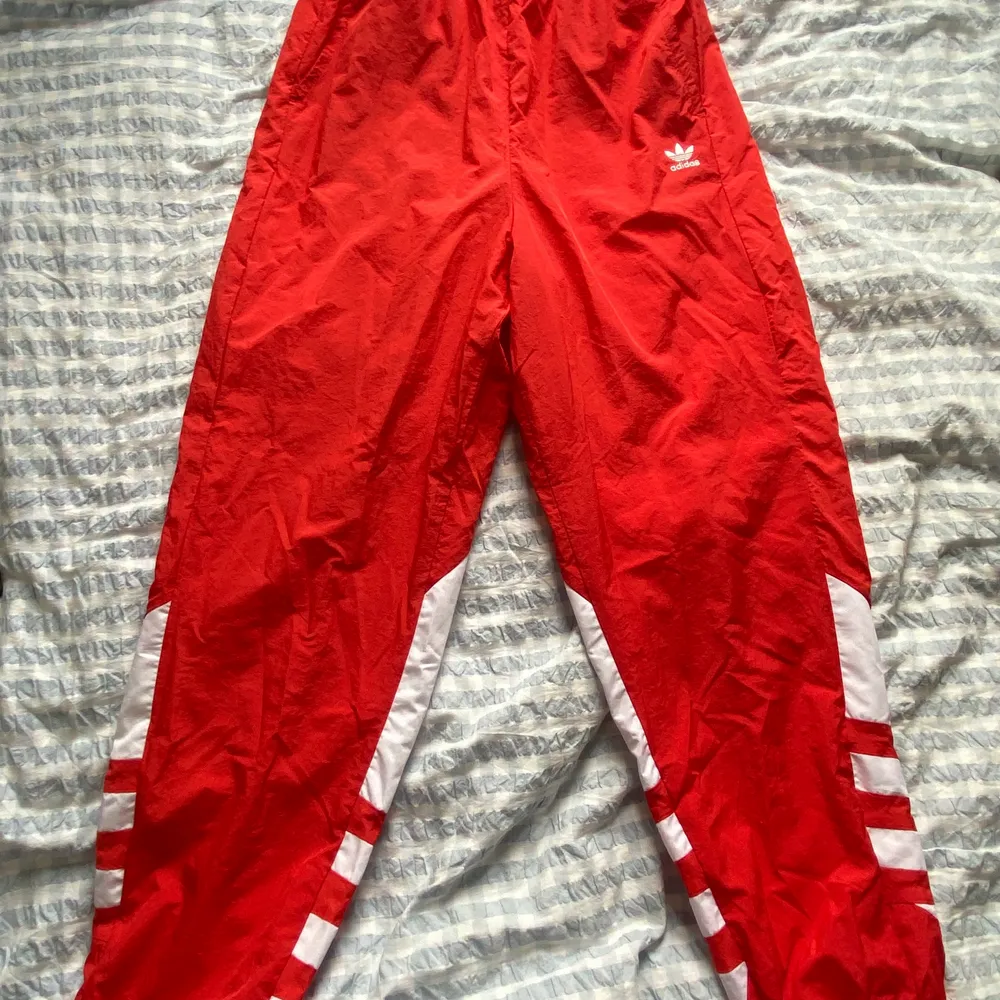 Ett par röda Adidasbyxor i windvreaker material, knappt använda! . Jeans & Byxor.