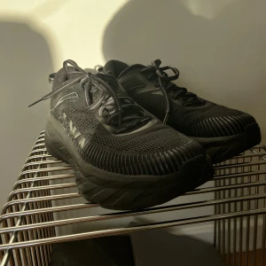 Hoka Bondi 7 - Säljer ett par Bondi 7 i nyskick. Endast testade.  Storlek 41 1/3.   Ingen kartong ingår.  Helsvarta, perfekt som Sneaker eller bekväm löparsko.   