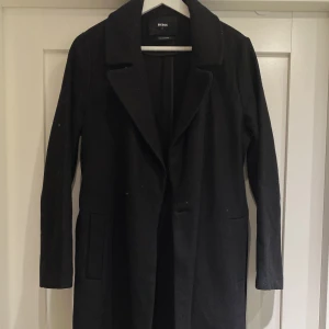 Svart ullkappa - Svart ankellång kappa i ull. Storlek S. Knäpps med en knapp samt skärpe som knyts. Skick som ny. 