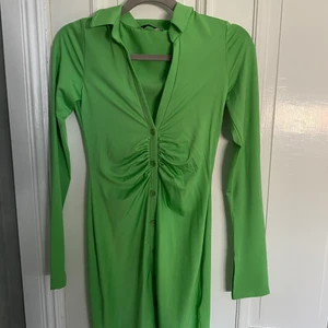 Grön festklänning  - Säljer nu min sjukt coola gröna festklänning!! Endast använd en gång, silkeslent mjukt material som funkar både till sommarn och till klubben!! Slitsar längst ner på båda ärmarna, knappdetaljer samt markerad midja! Köptes för ca 400kr. Köparen står för frakt, priset kan diskuteras❣️❣️💌