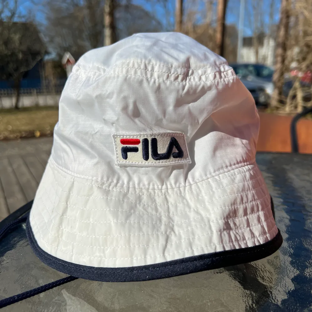 Fila bucket hat i storlek one size. Sitter fast ett snöre i hatten. Gjord av polyester. Köpt från Zalando, och har bara använts vid ett fåtal tillfällen så den är i bra skick.. Asusteet.