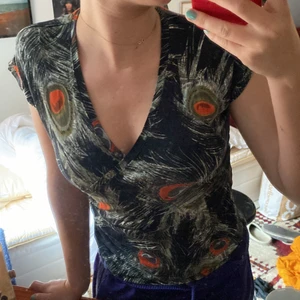 Påfågel topp - En tröja från indiska med påfågelmönster. V-ringad. Inte använd köpt second hand. Tugget är stretchigt så Xs-S kanske t.o.m. M men då blir den lite tajtare. 