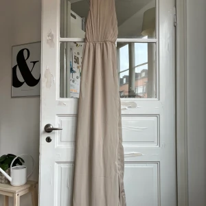 Lång festklänning - En oanvänd långklänning från Bubbleroom. Har ej använts pga inställt bröllop. Har knäppning med knappar och dragkedja på ryggen. Slits på ens sidan.