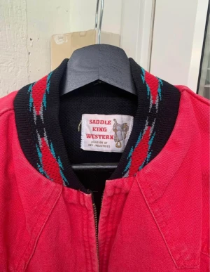 Vintage jeansjacka  - Supersnygg röd jeansjacka med broderat mönster runt kragen. Köpt secondhand, jag har använt den 2-3 gånger bara. Med dragkedja  och tjockare material på insidan. Storlek saknas men skulle säga att den är en L! Möts gärna upp i Stockholm! 🙏