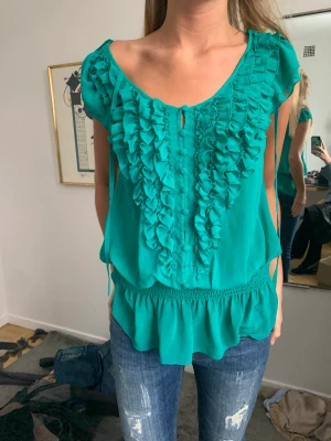Turkos blus - Säljer denna så söta blus i turkos som man kan ha på två sätt. Står ingen storlek i men skulle säga S/M väldigt stretchig. Från märket Lipsy. En knapp har gått av. 