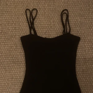 Tajt svart klänning - Svart klänning som är väldigt tajt och är en simpel kort längd som går ner till mitten av låren och den har spaghetti straps.