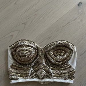 Bustier med gulddetaljer - Bustier från BIKBOK, strl. M med gulddetaljer. Jättefin under en vit kavaj. 