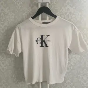 Ikonisk vit t-shirt 100% bomull med vintagekänsla från CK butik i Amsterdam. Löst uppvikta ärmar. Sömmen har släppt på insidan bak, enkelt att fixa, se bild.